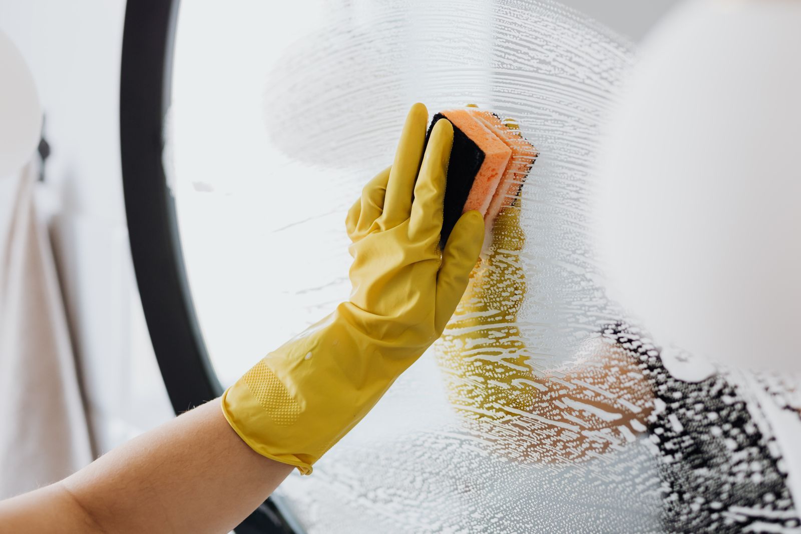 Gloved hand polishing interior glass until it disappears