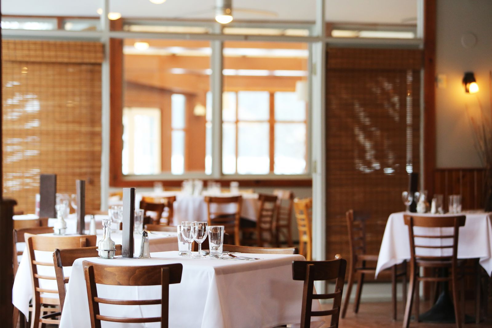 Sunlit restaurant dining room set with white tablecloths