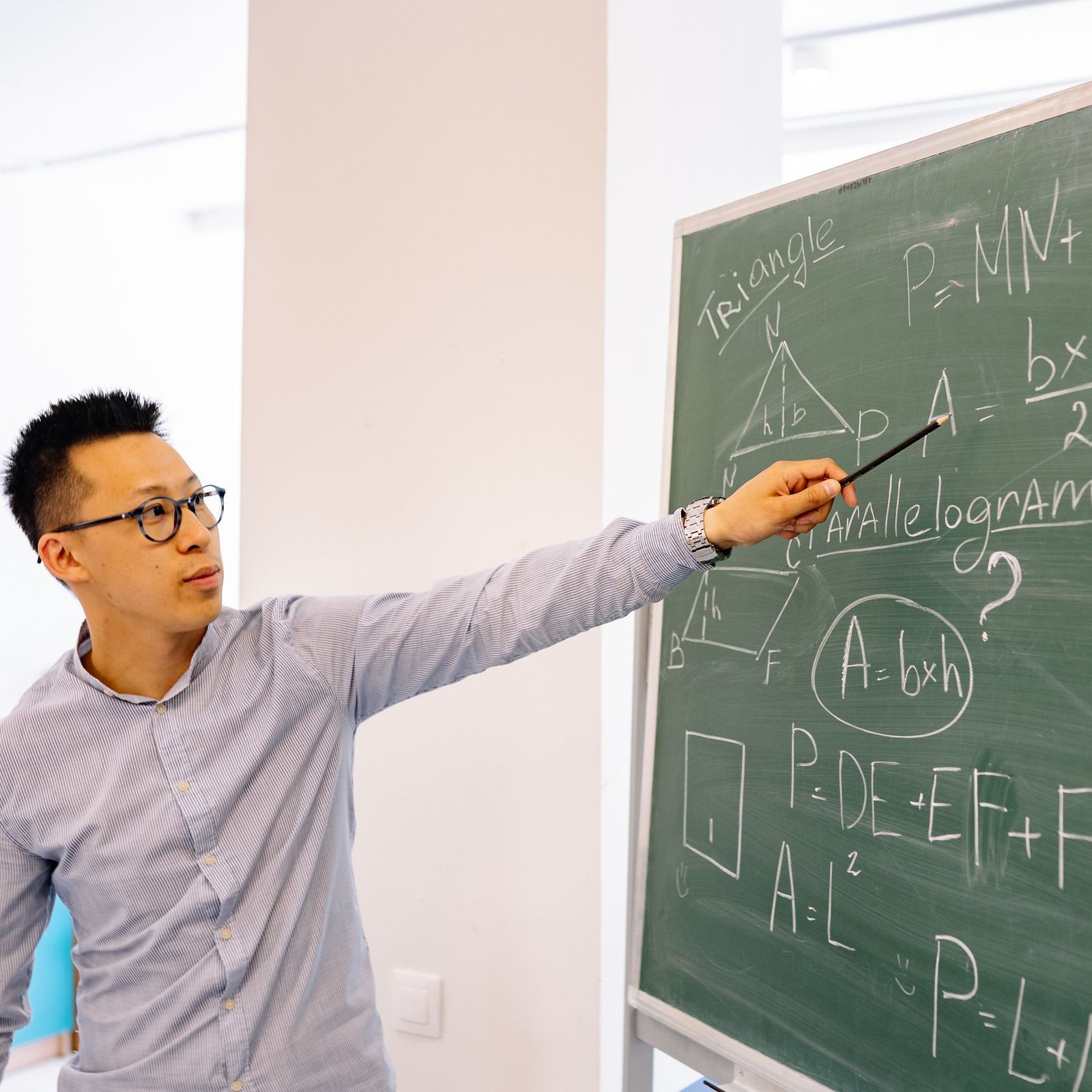 Teacher working through a math problem at the blackboard