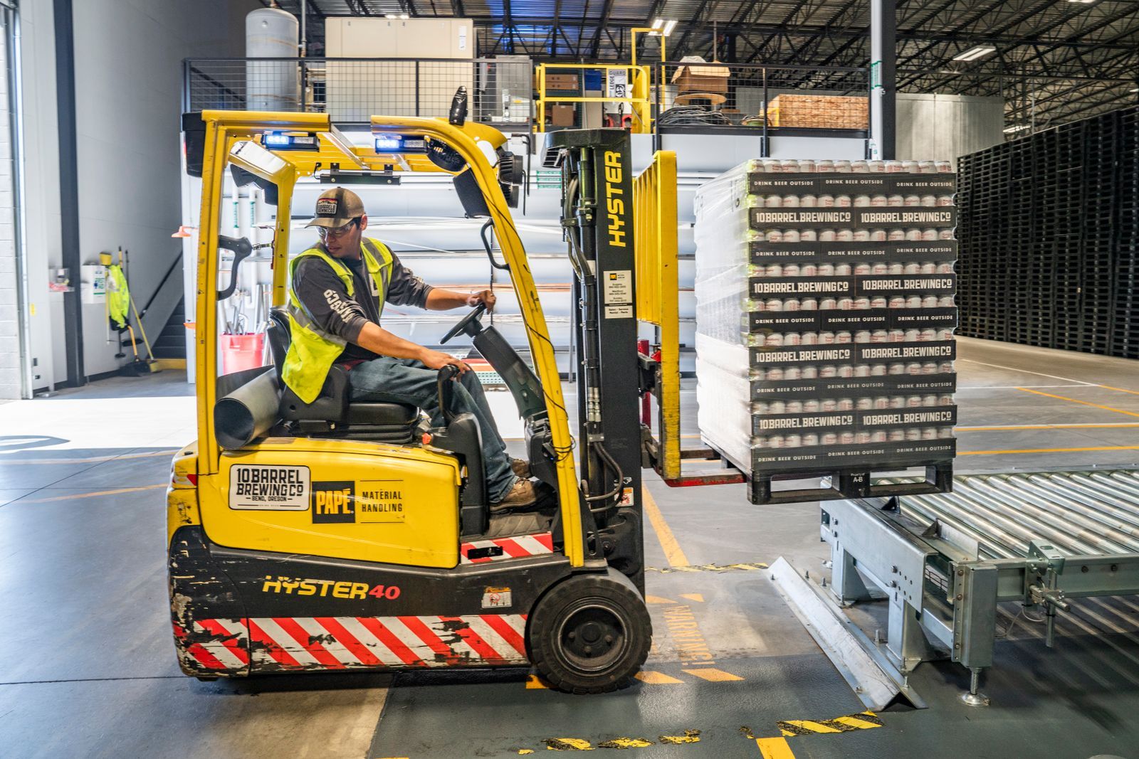 Forklift operator moving pallets inside a warehouse